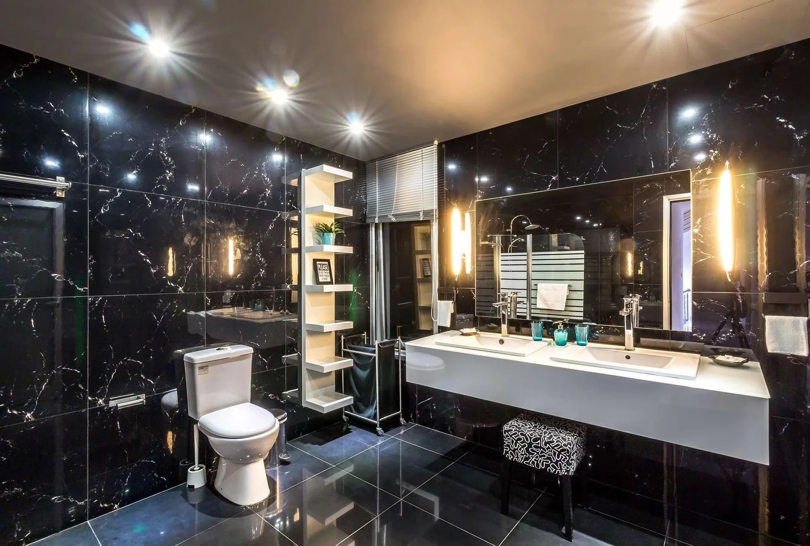 Black marble bathroom with double white vanity, vertical lighting and patterned floor