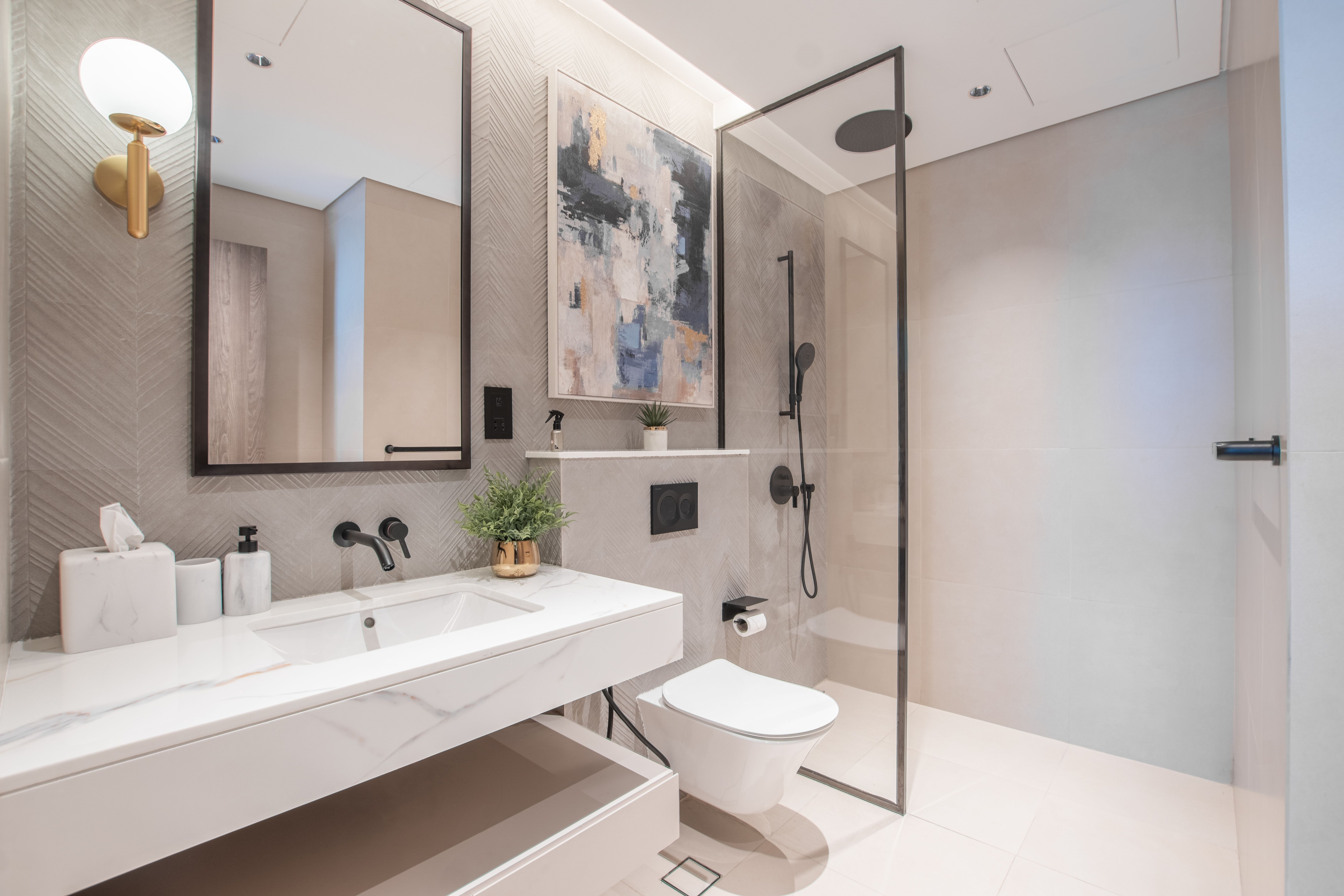 Modern Dubai bathroom with marble vanity, black fixtures, herringbone tiles and glass shower