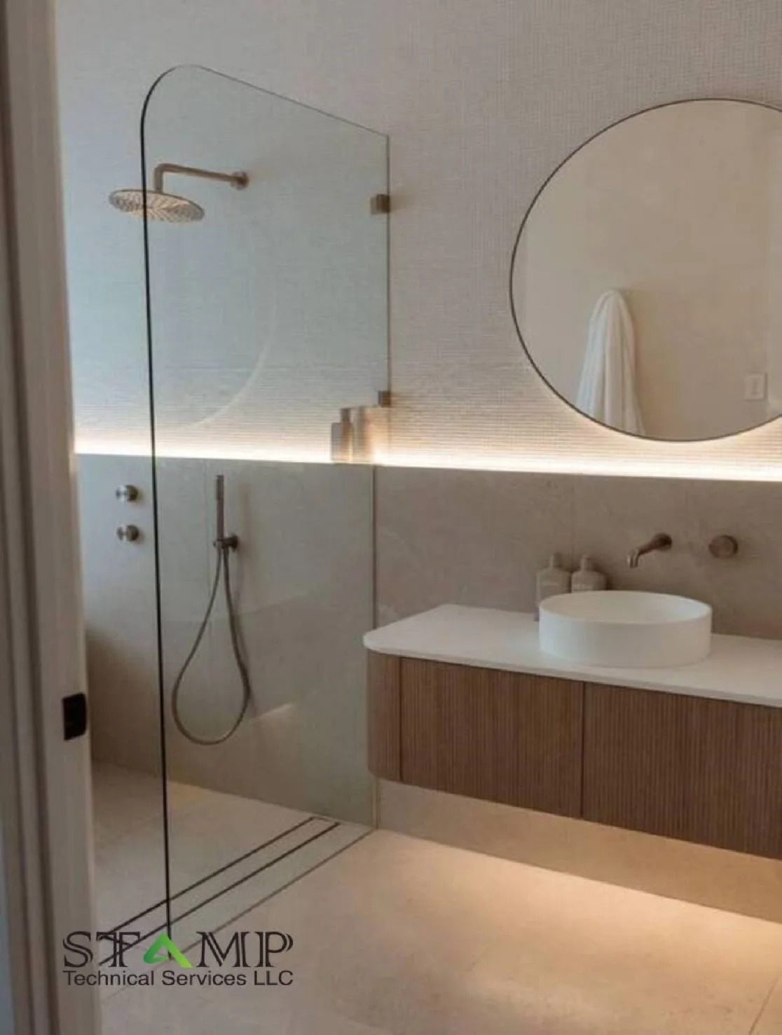 Warm wood vanity with round mirror and curved glass shower with LED strip