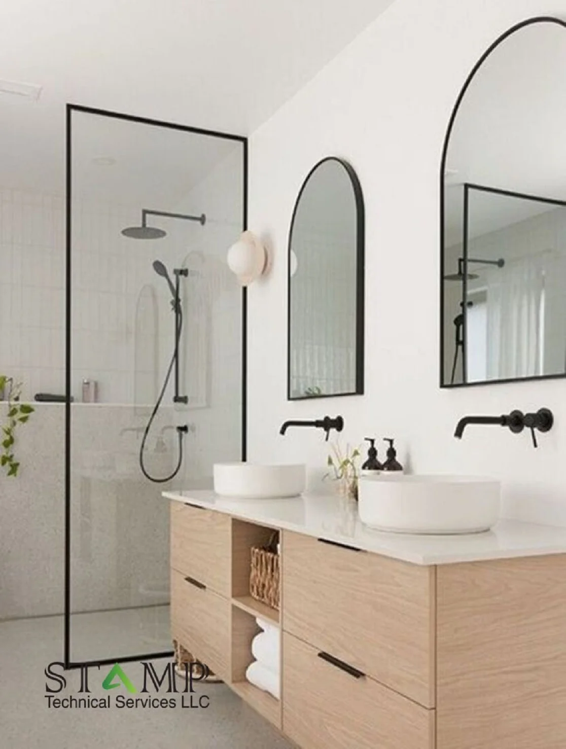 Double vanity bathroom with black framed glass shower and wood cabinets