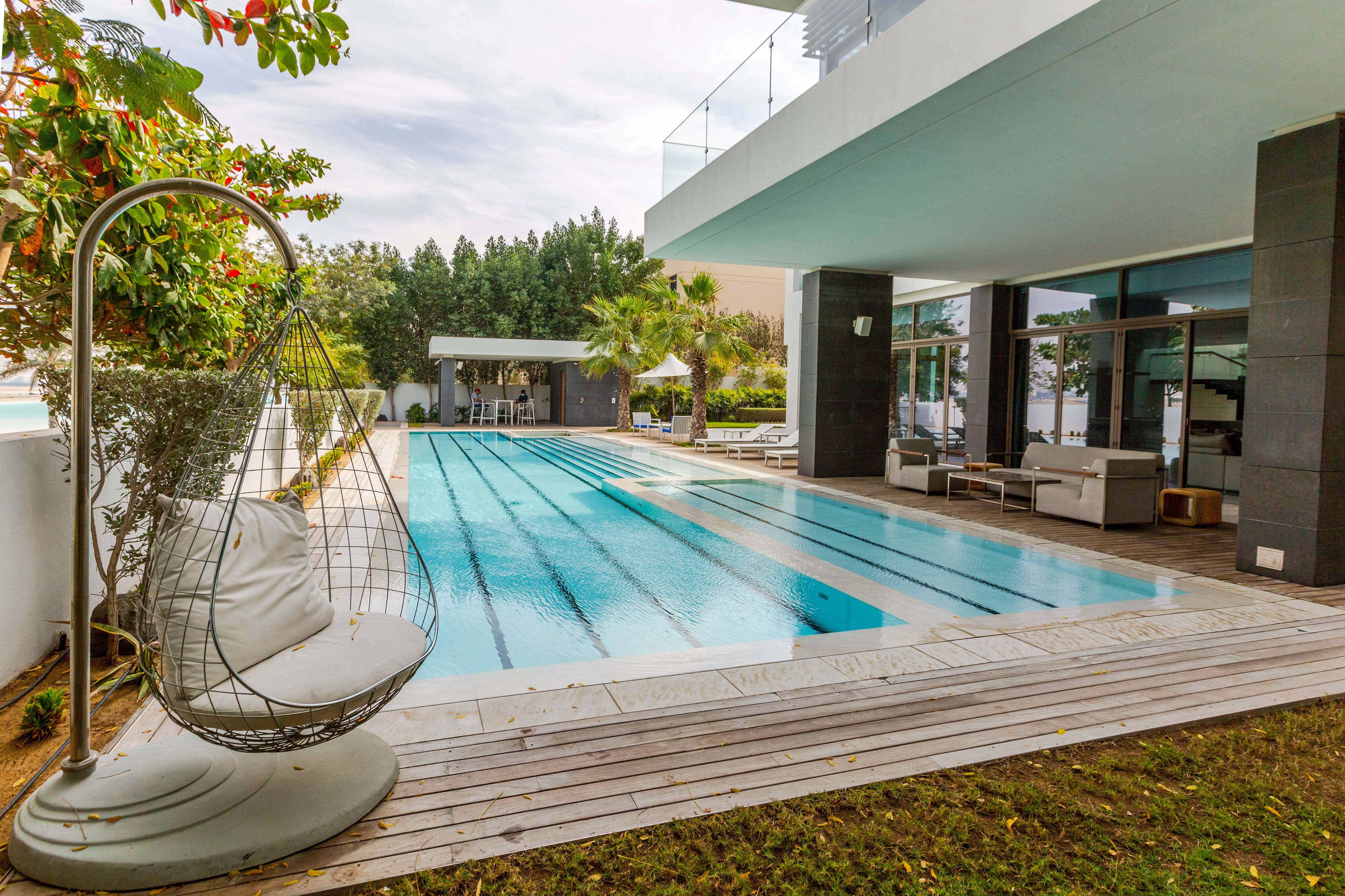 Landscaped villa garden in Dubai with pool, hanging chair and decking