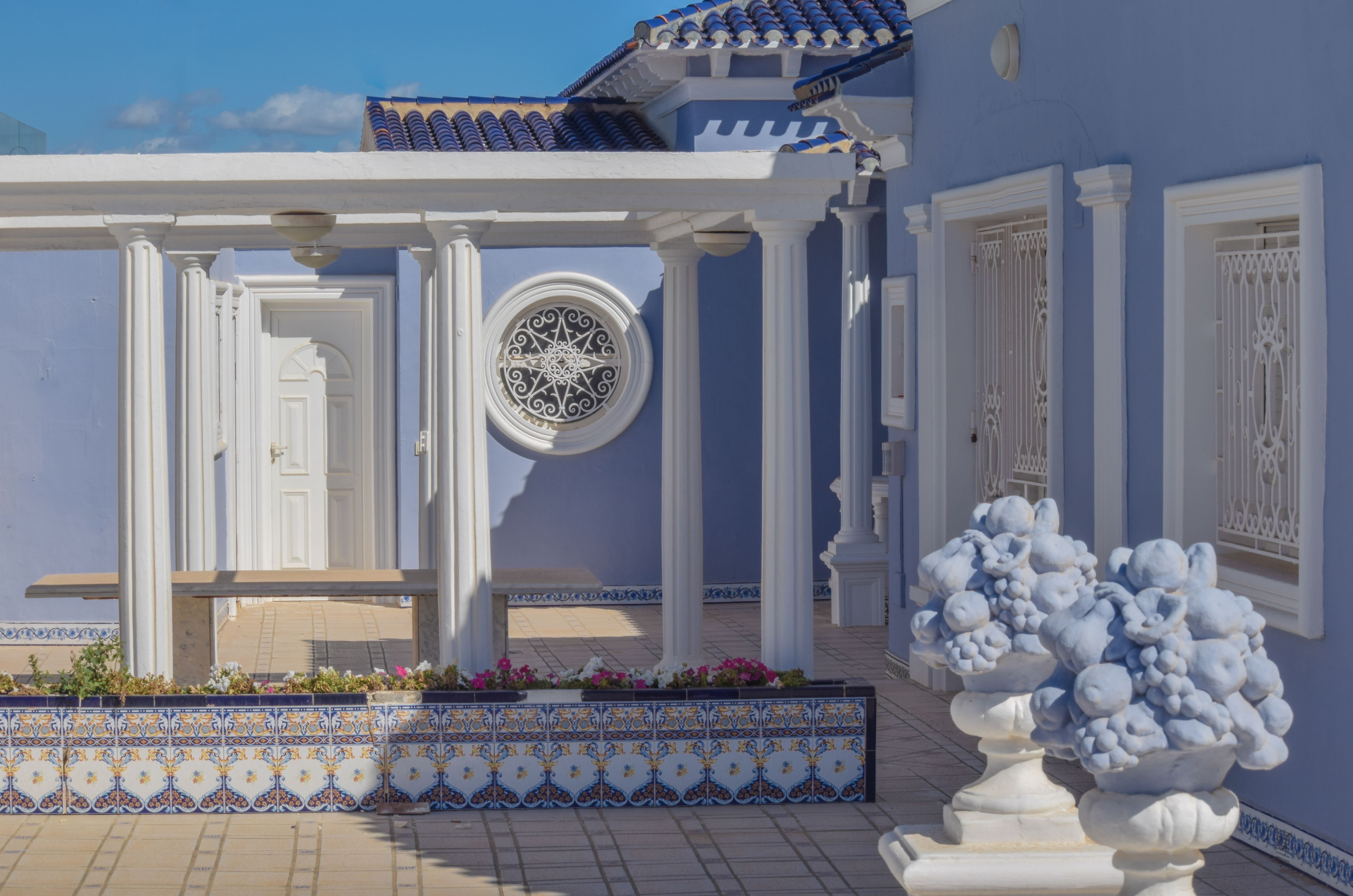 Blue villa exterior with columns and decorative round window in Dubai